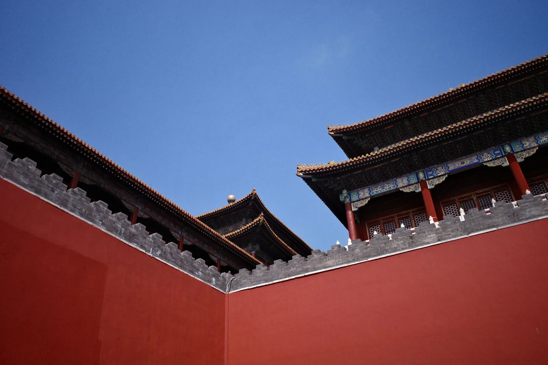 The red wall and layered roofline of the Forbidden City against a clear sky