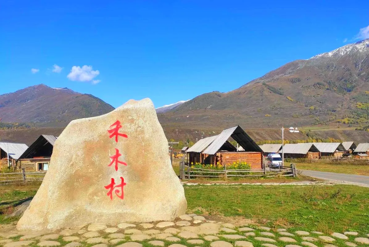 Carved stone marking Hemu village beside Tuva wooden cabins