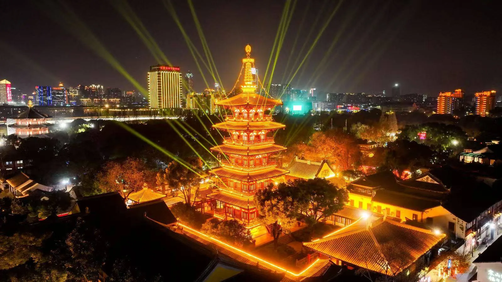 The New Year bell ceremony at Hanshan Temple, Suzhou, laser beams over the pagoda and grounds. The 46th edition shown; the 48th falls on December 31, 2026.