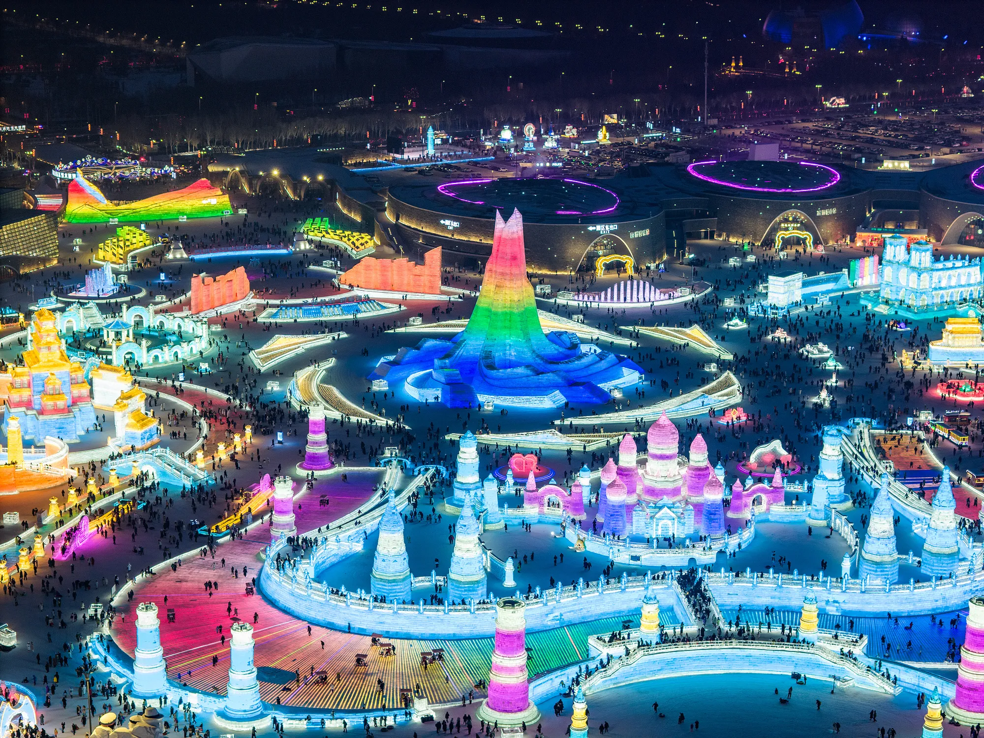 The rainbow-lit main tower at Harbin Ice and Snow World at night. New Year's Eve falls about two weeks into the park's season, after the opening rush and before the Spring Festival peak.