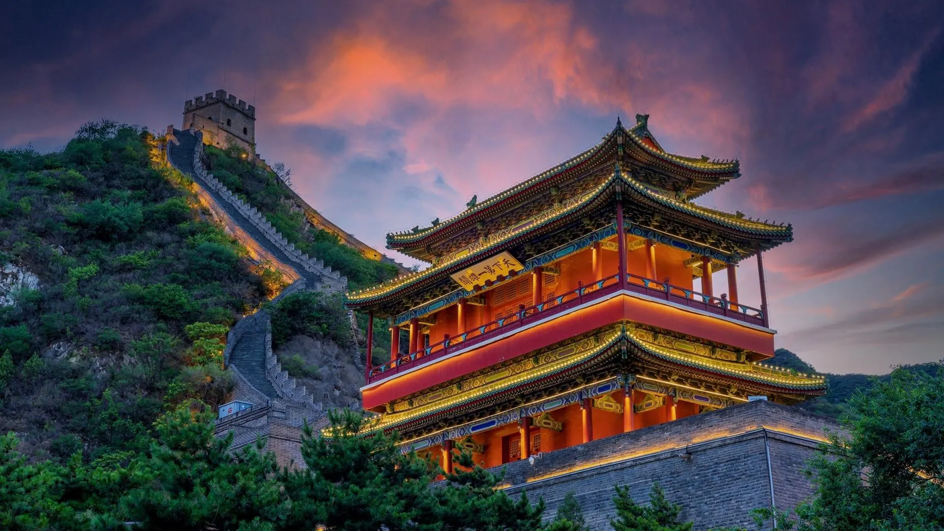 Juyongguan Great Wall at dusk, the "Number One Majestic Pass" gate lit under a burning sky. The fortress hosted one of Beijing's two official countdown stages, admission by invitation only.