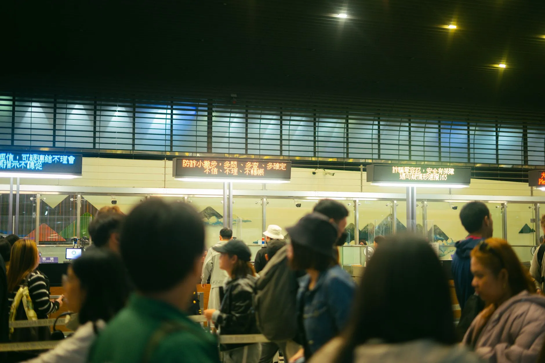 Travellers queue at airport check-in desks beneath a departure information board