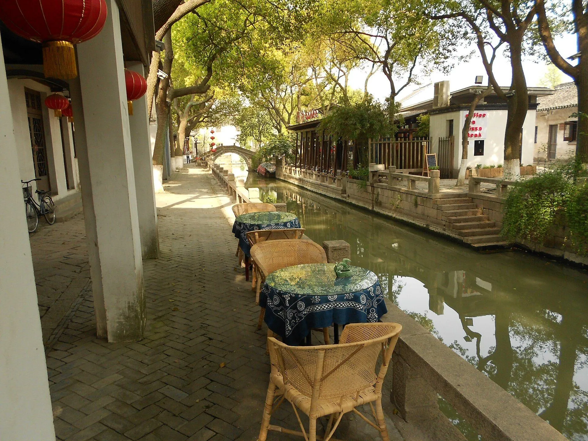 Teahouse tables beside the Tongli canal, with a stone arch bridge behind