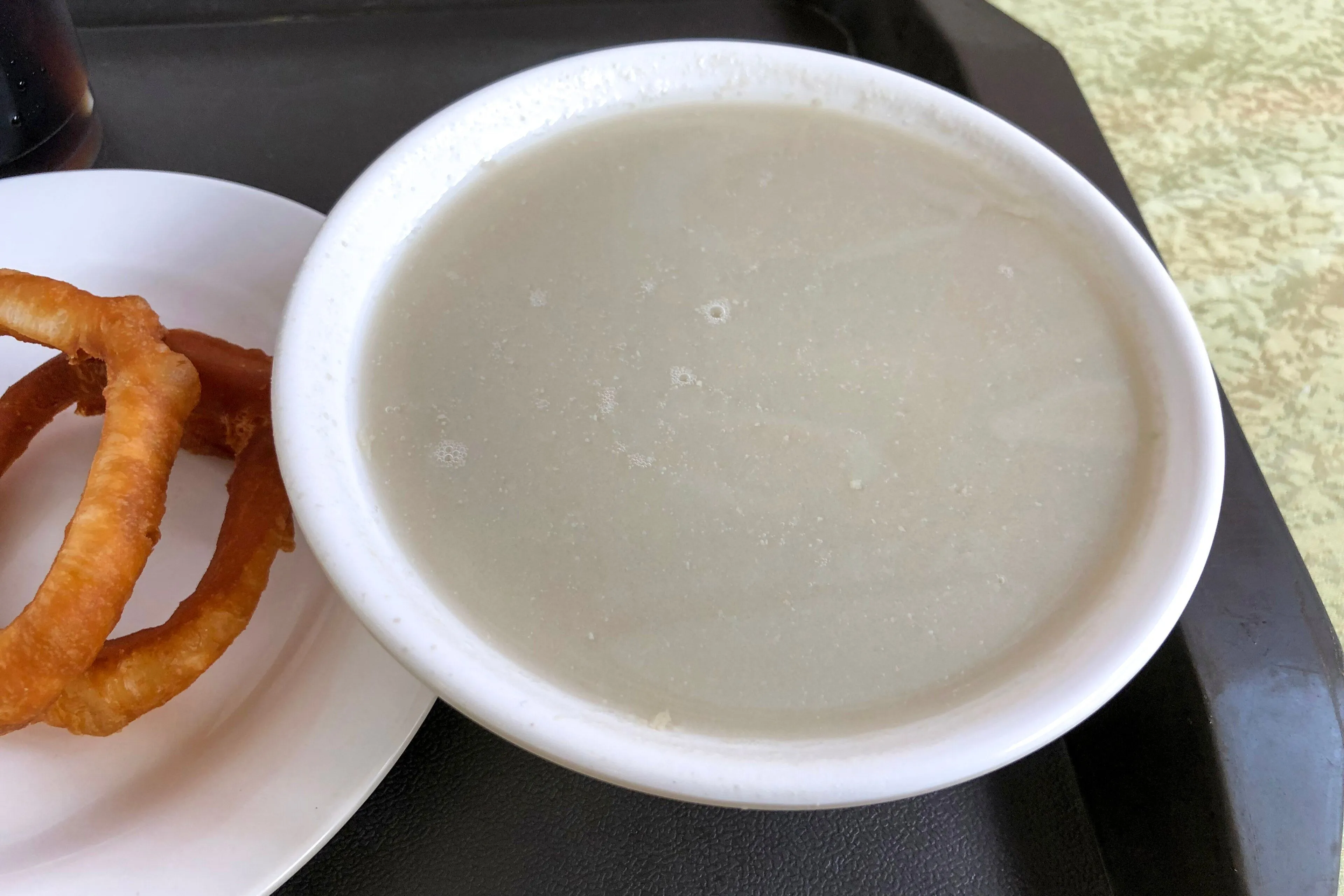 Douzhi with jiaoquan — fermented mung-bean drink and a fried ring, the Beijing breakfast that divides visitors
