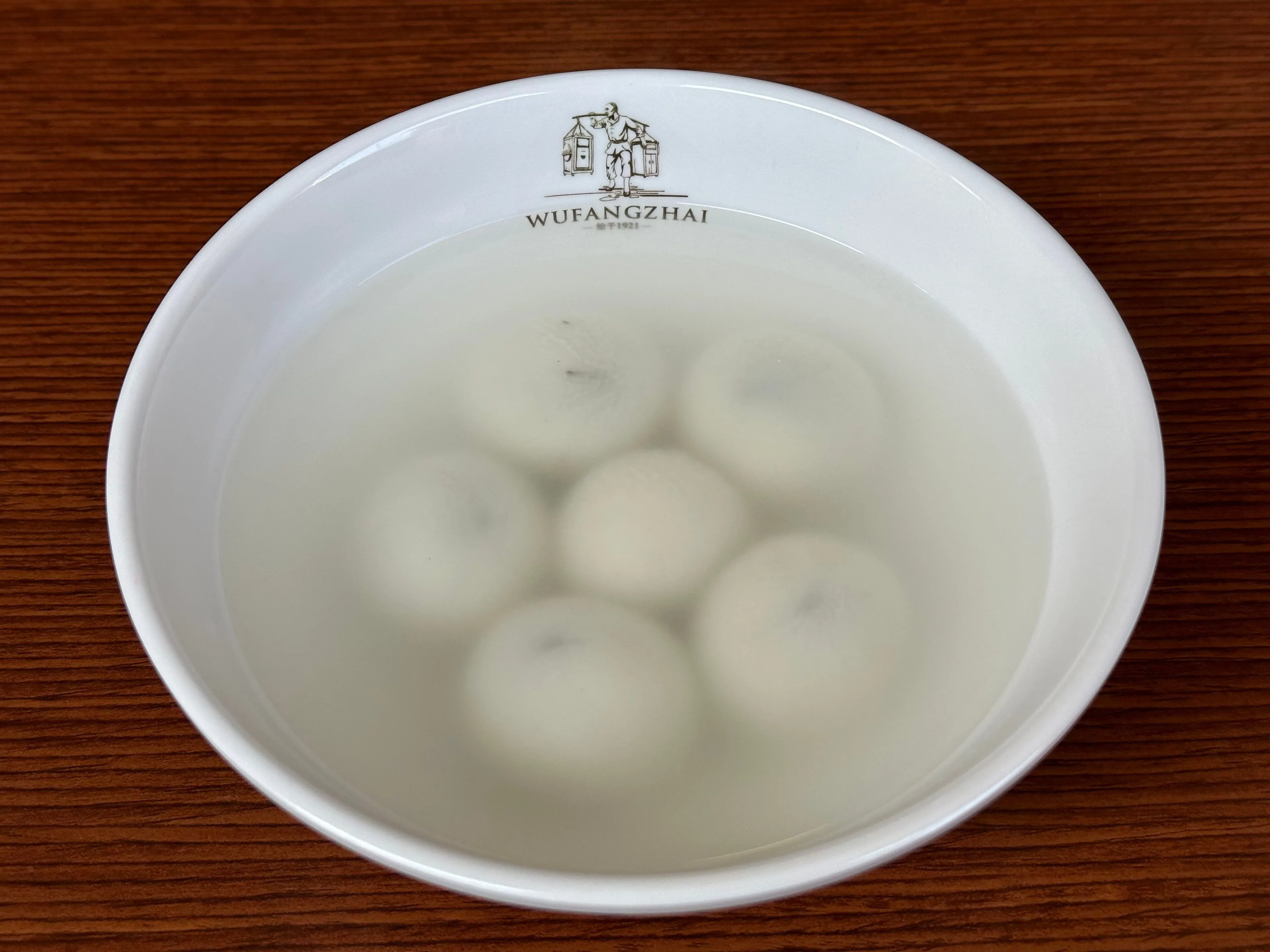Sweet glutinous rice dumplings in a bowl carrying the Wufangzhai brand