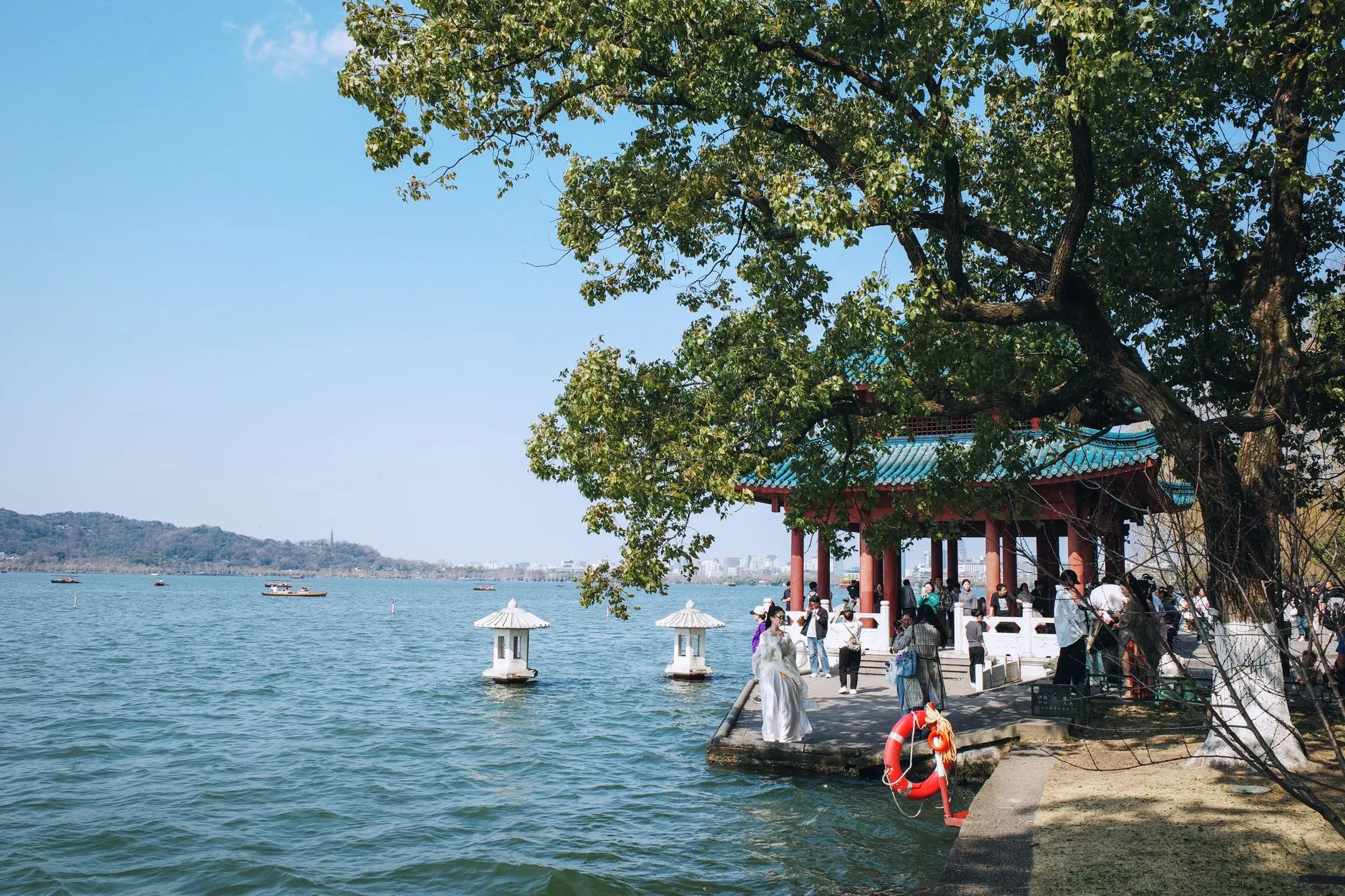 A lakeside pavilion and visitors at West Lake, Hangzhou, in spring