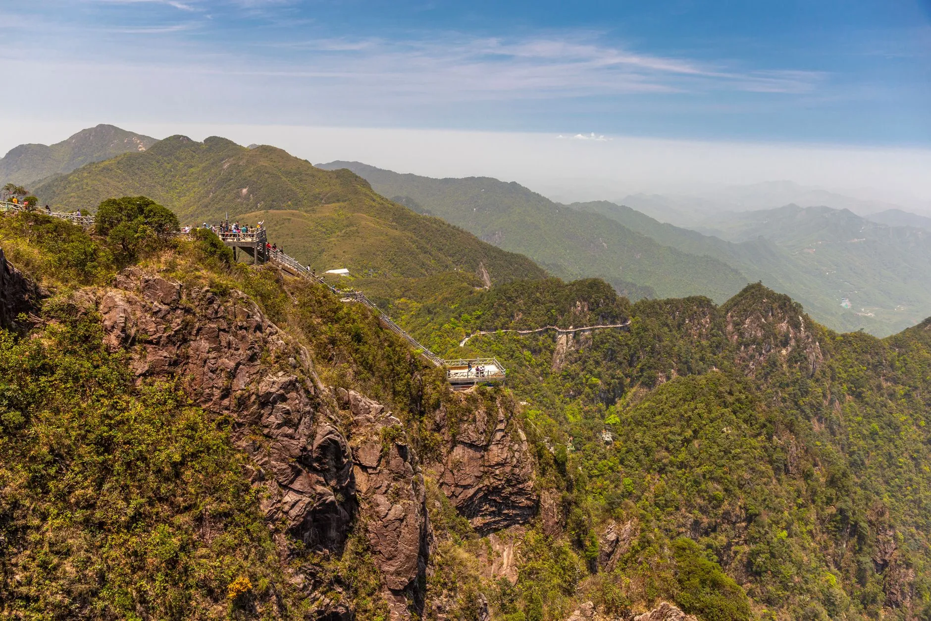 Travellers at a mountain-top lookout over forested ridges