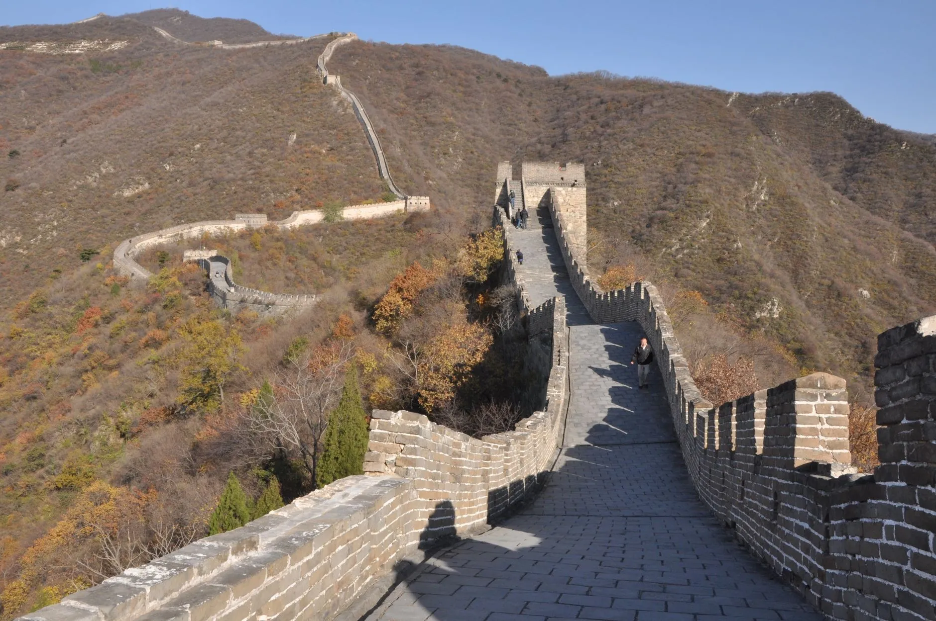 Hikers ascending the Great Wall steps through autumn foliage