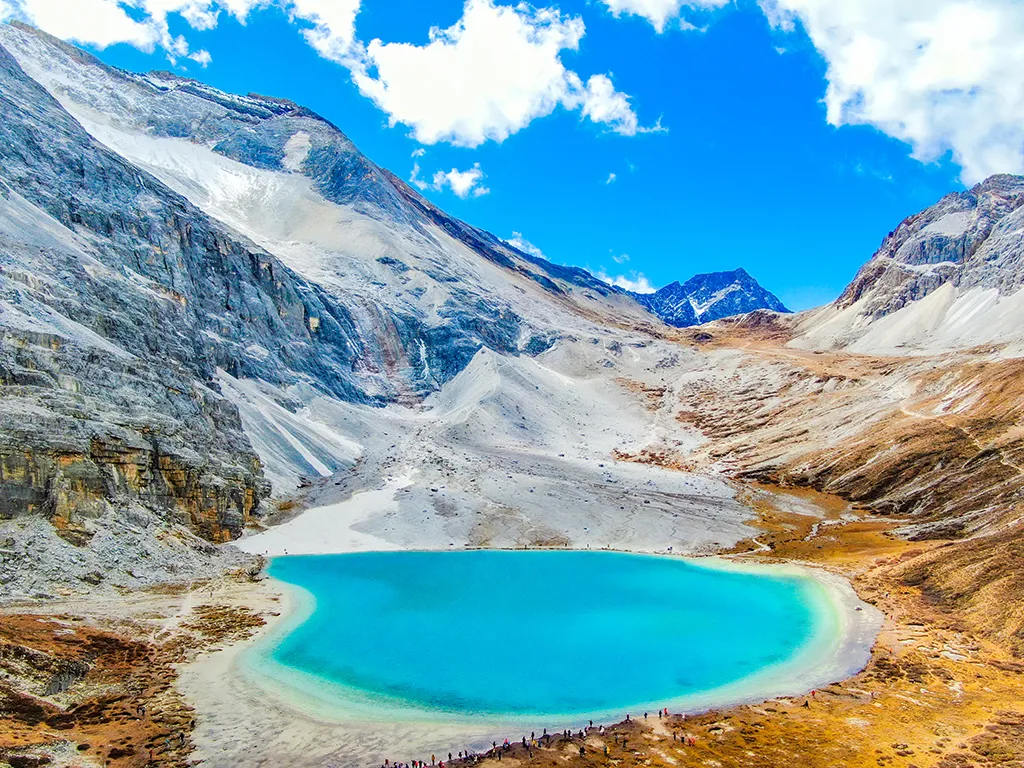 Turquoise alpine lake surrounded by forest at Yading