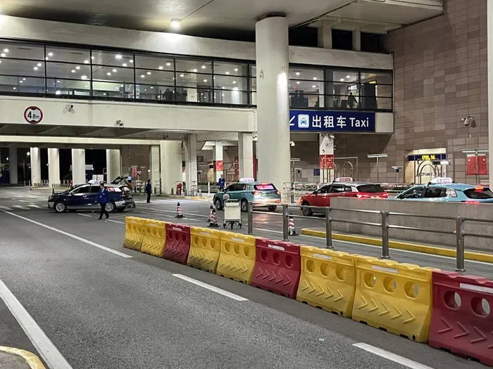 Taxis lined up at a Chinese airport taxi rank, waiting for passengers under a blue "Taxi" sign
