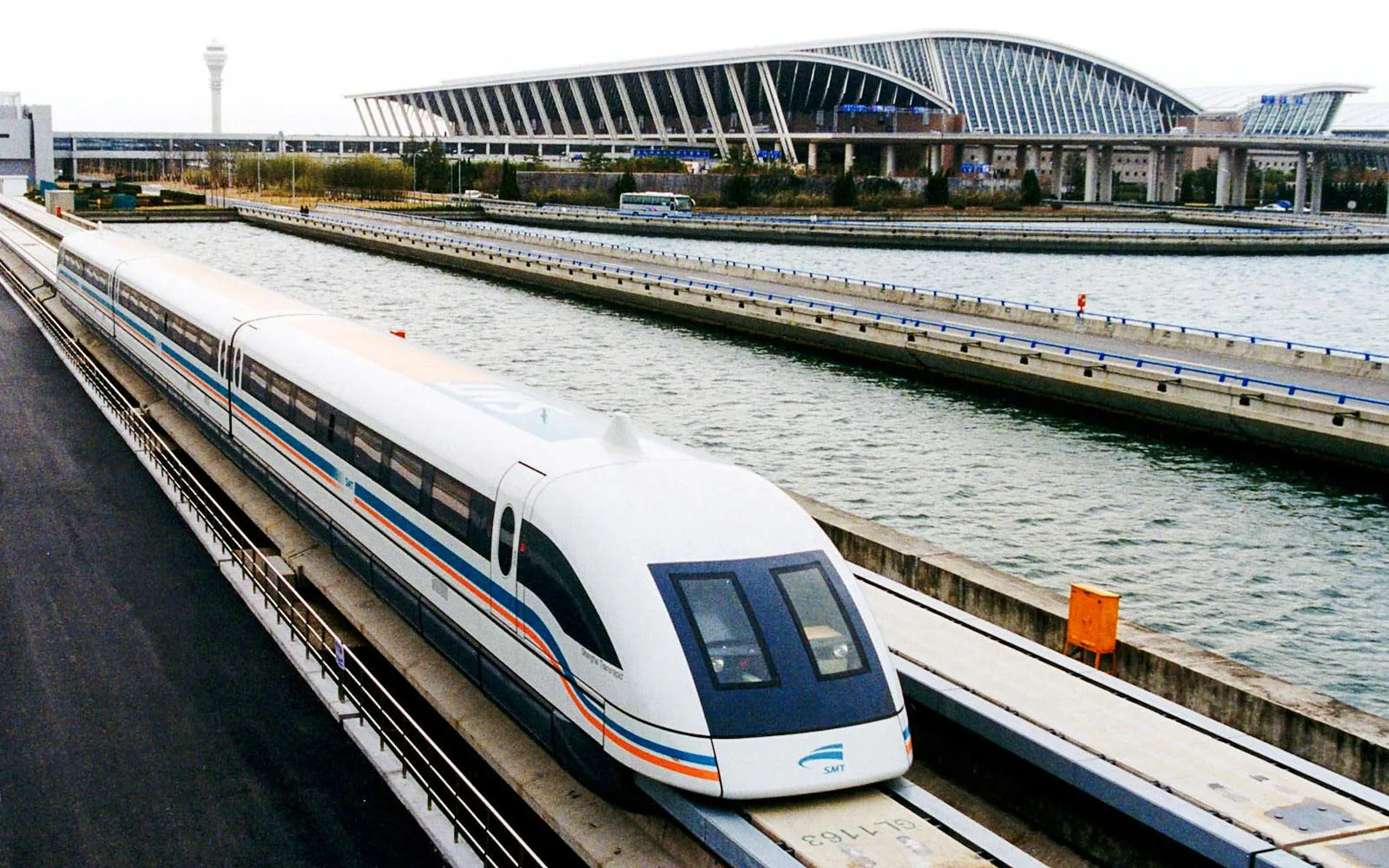 The Shanghai Maglev train on its elevated track at Pudong Airport, with the T1 terminal and control tower in the background