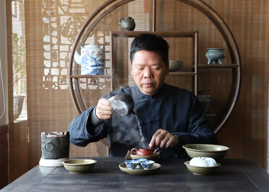 A man pouring hot water into a teapot at a Chinese tea table with rising steam
