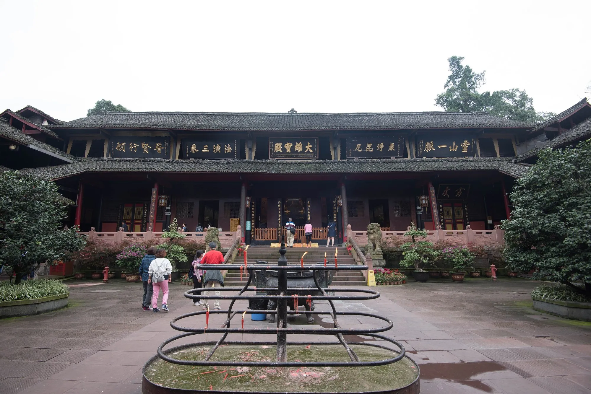 The inner courtyard of Baoguo Temple on Mount Emei, with a row of plaques along the main hall and a censer on the axis