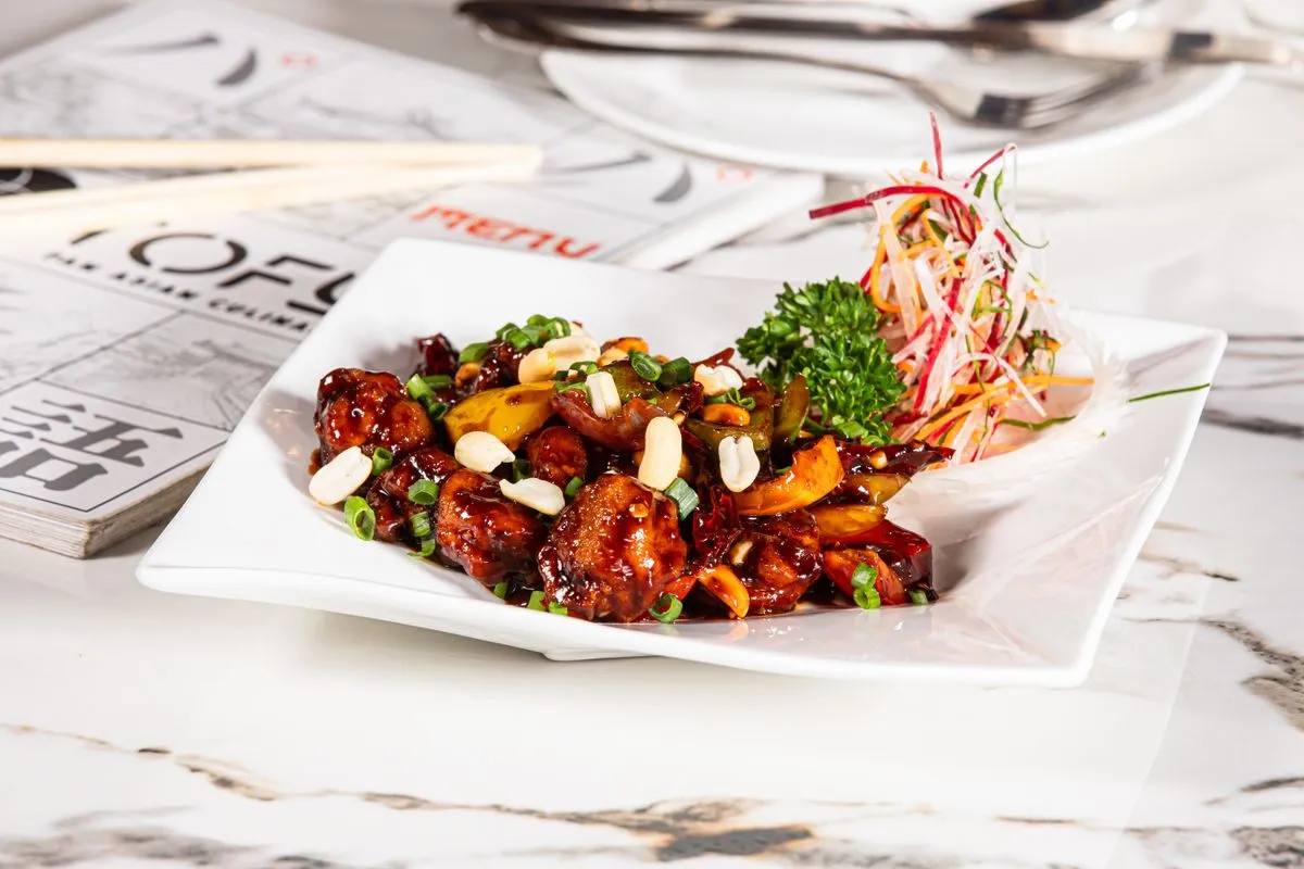 Kung Pao Chicken served on a white plate with peanuts and chili peppers