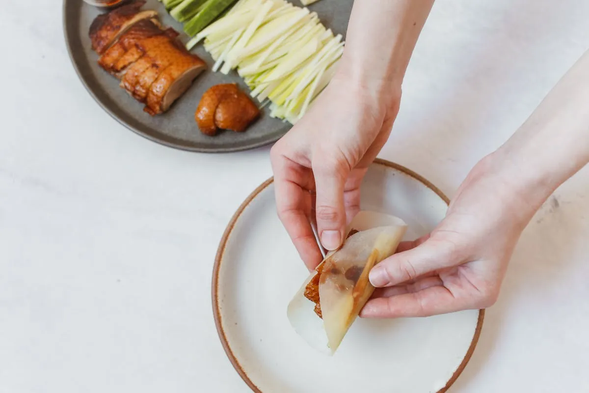 Wrapping sliced Peking Duck in thin pancakes with scallions and hoisin sauce